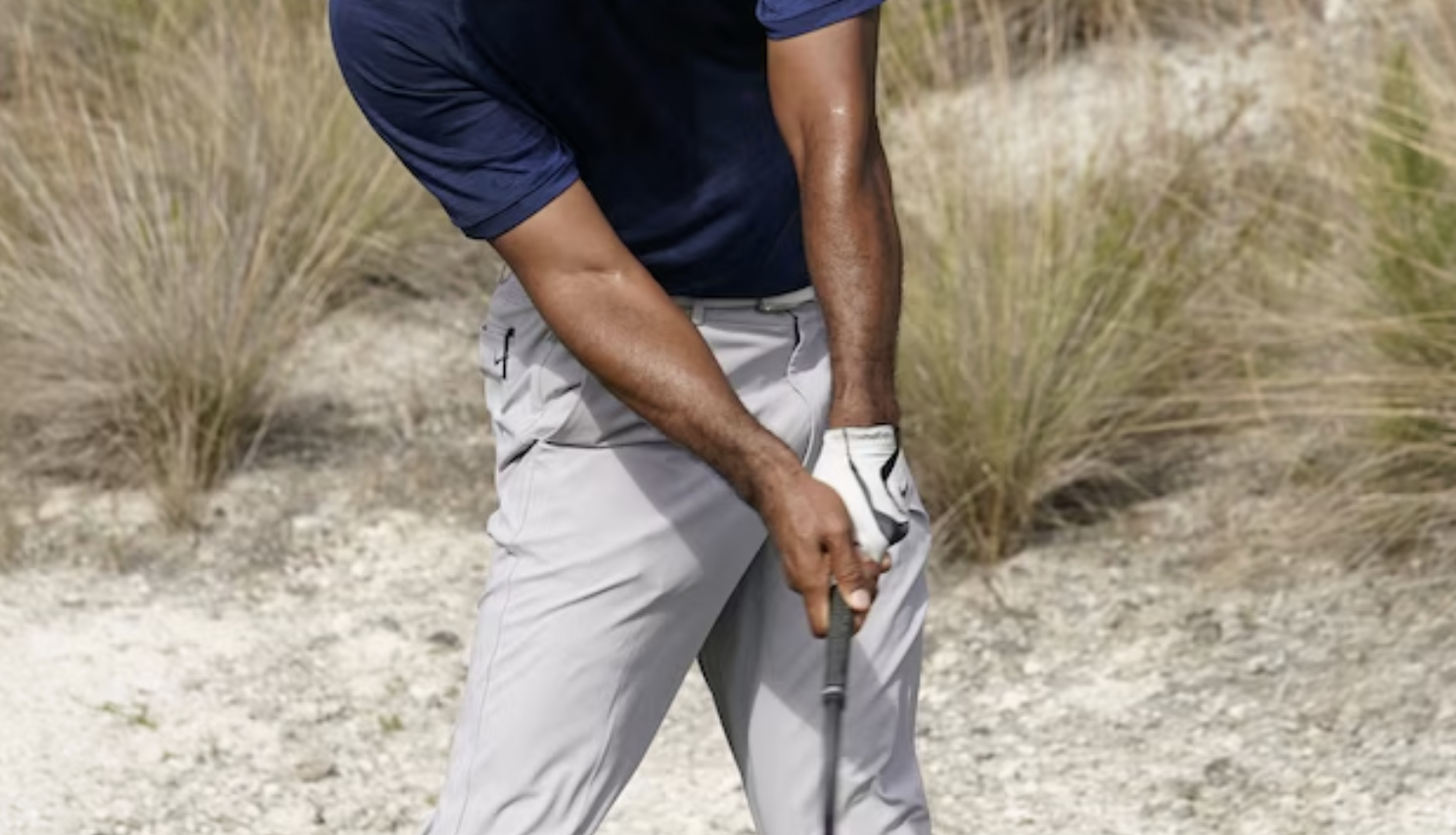 Golfer at full extension through impact in Austin, Texas showing bowed lead wrist flexion and extended trail wrist that control clubface, shaft lean, and ball striking in the golf swing