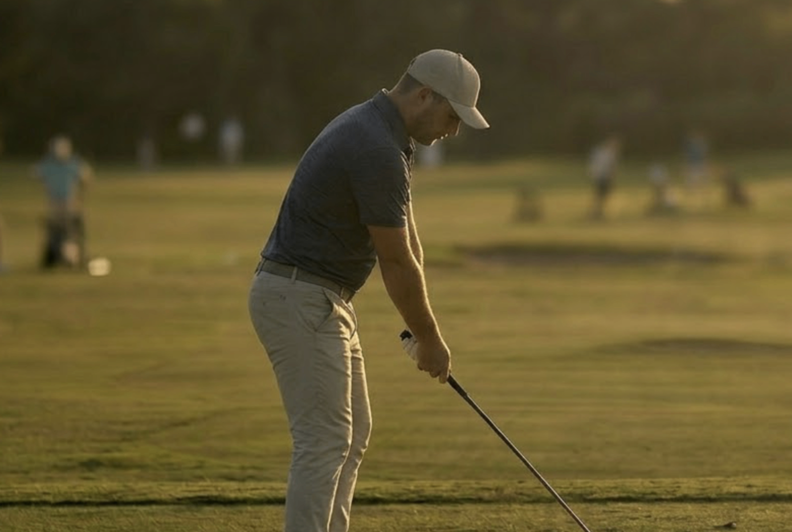Golfer practicing iron shots at sunset on an Austin driving range, working on the contact and ball-striking needed to break 90 in golf