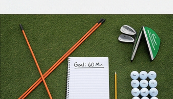Structured golf practice setup with alignment sticks and notebook